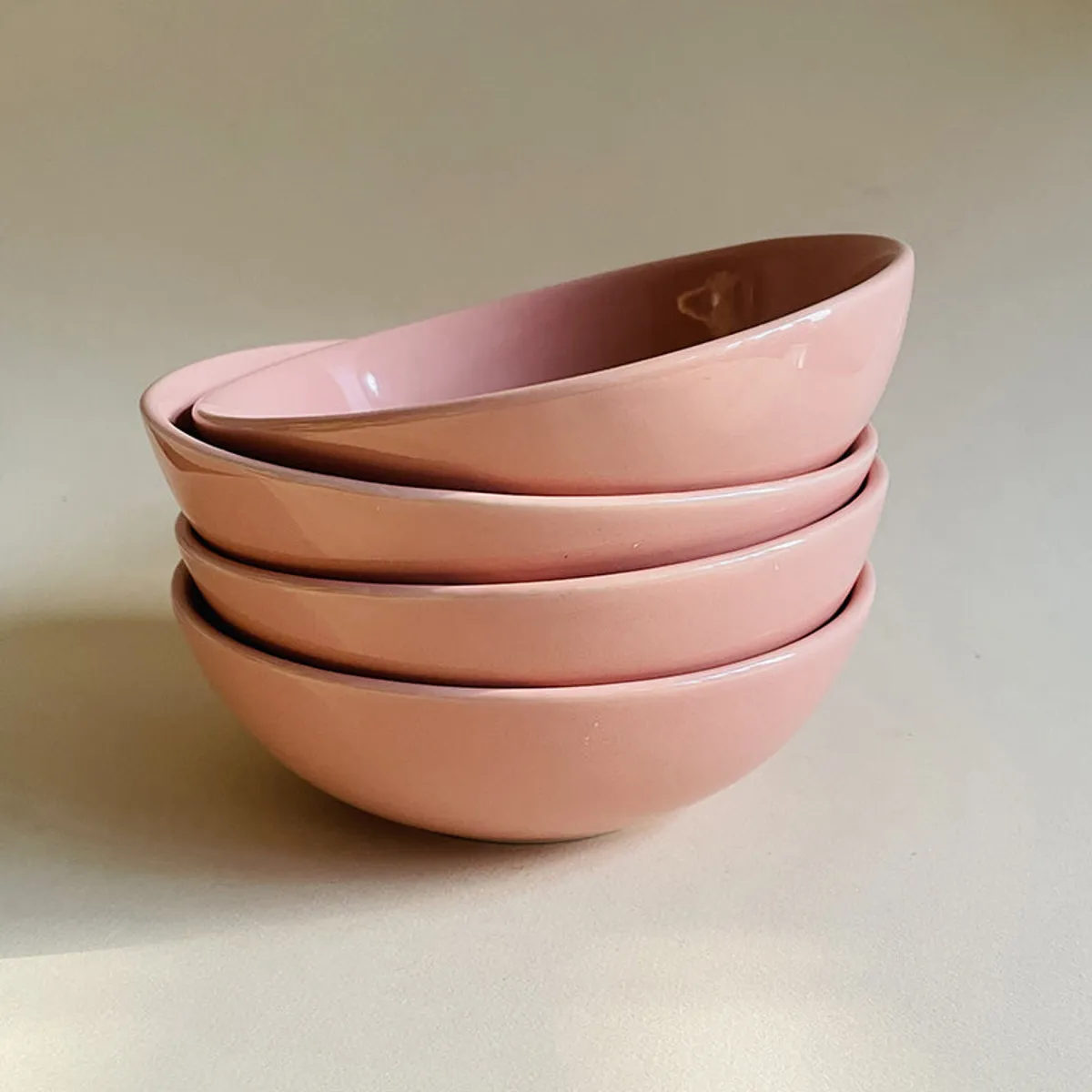 Four peach ceramic bowls stacked together, showing their rounded shape