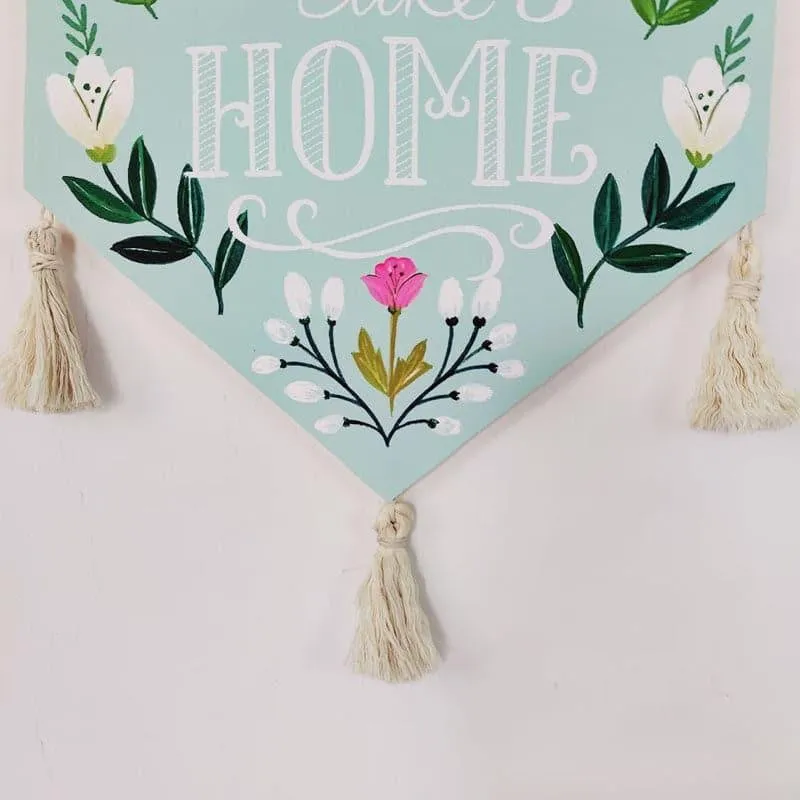 Close-up of floral wall hanging with tassels and pointed bottom