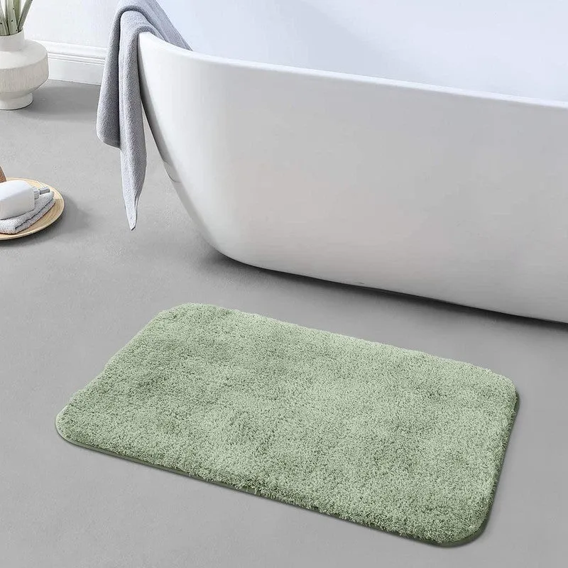Light green rectangular bath mat beside a white bathtub