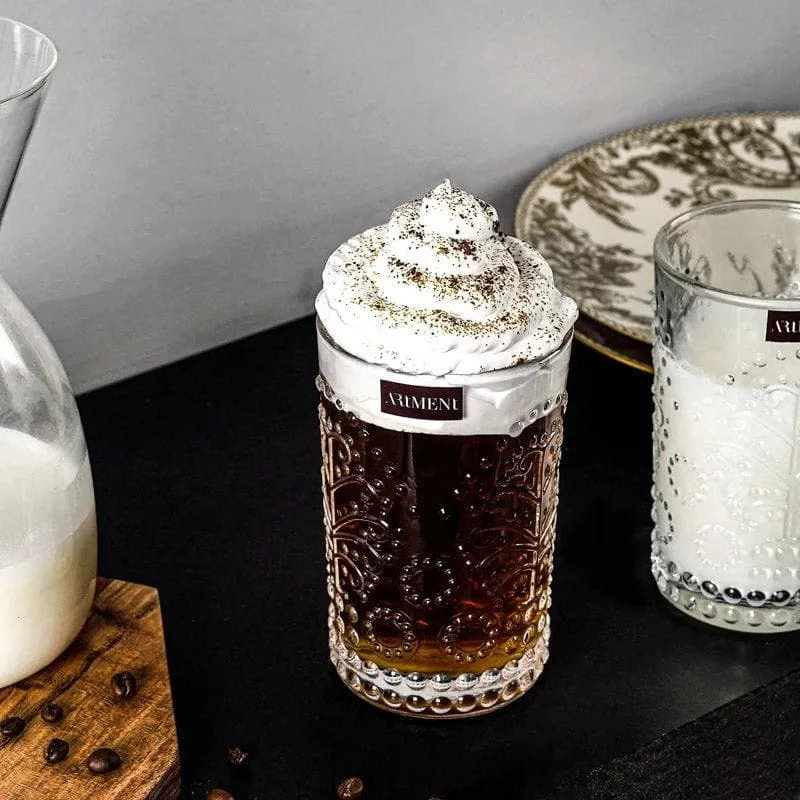 Embossed clear glass with dark drink and cream topping on a table