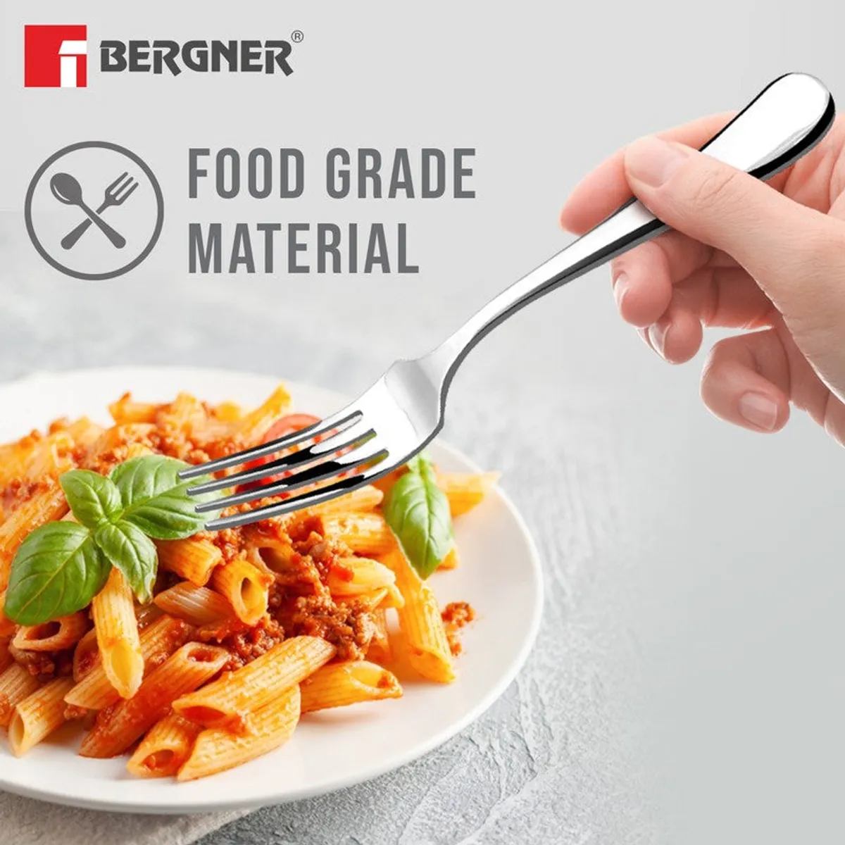 Hand holding a silver fork over a plate of pasta