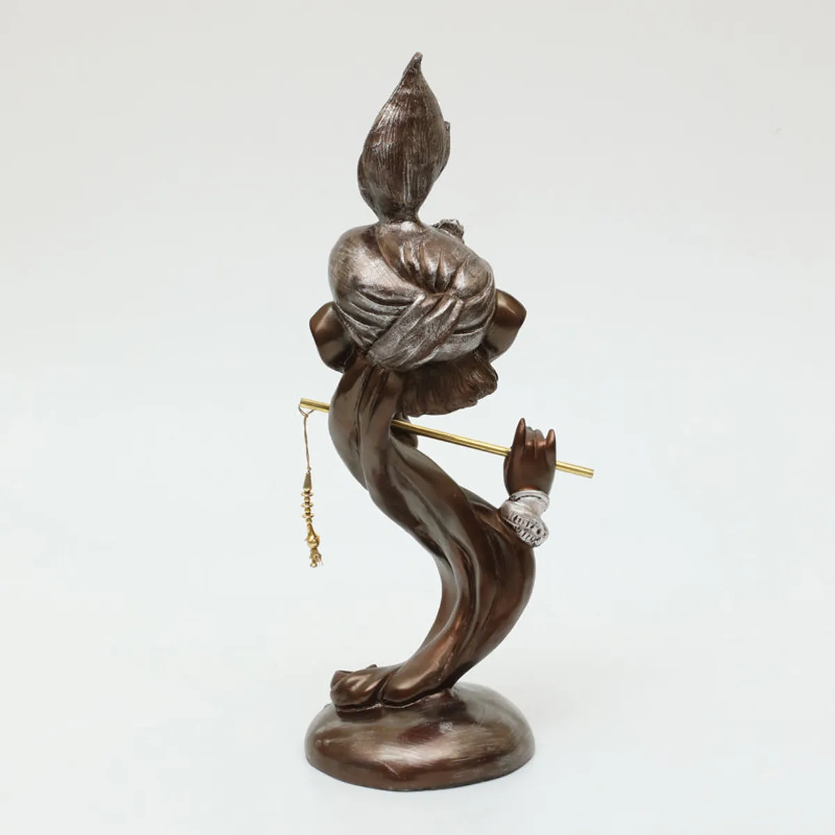 Rear view of a brown Ganesha showpiece holding a slim golden flute