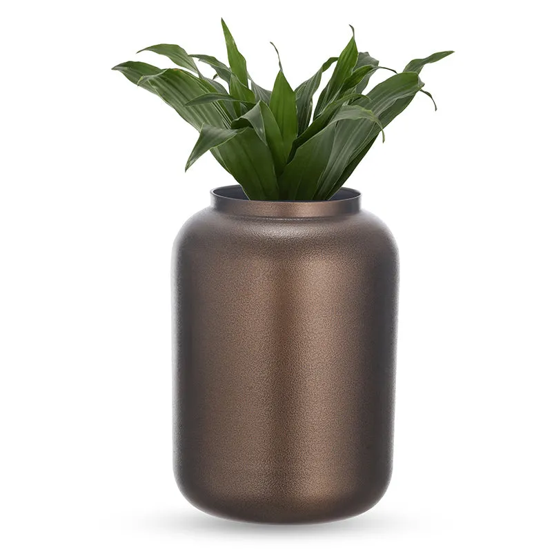 Brown cylindrical metal vase holding green leaves on a white background