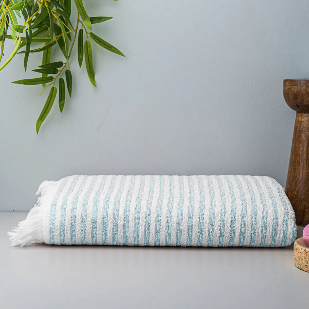 Folded light blue and white striped bath towel displayed on a bathroom surface.