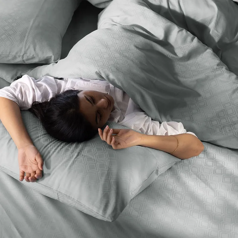 Close view of a light grey geometric duvet cover with a person resting on it