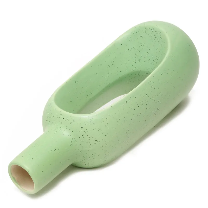 Top angled view of a green speckled donut vase lying sideways