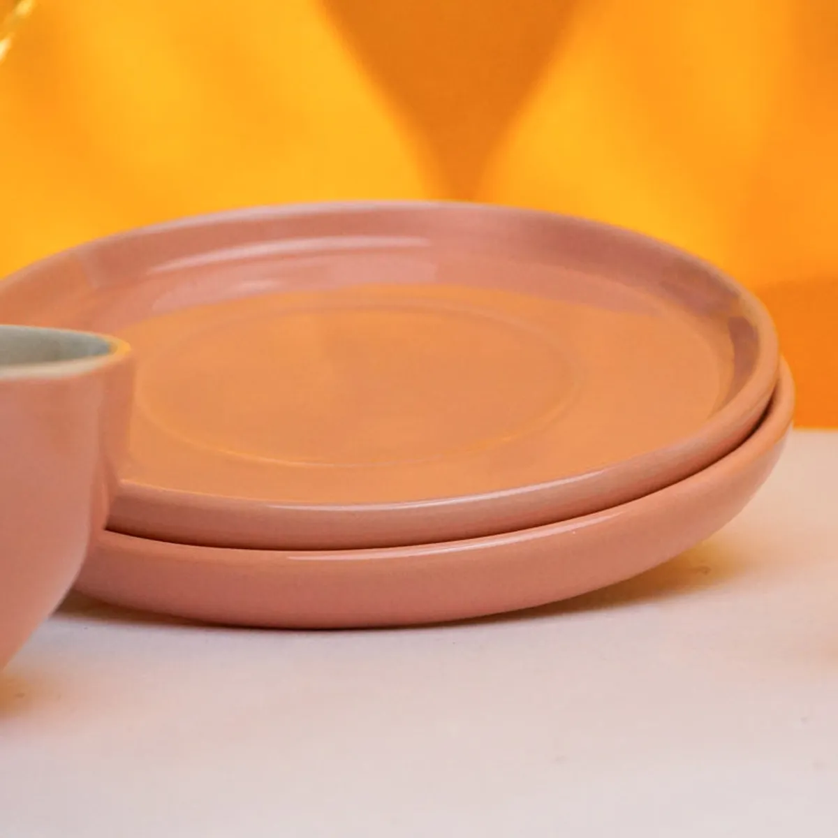 Stacked peach-pink saucers beside a cup
