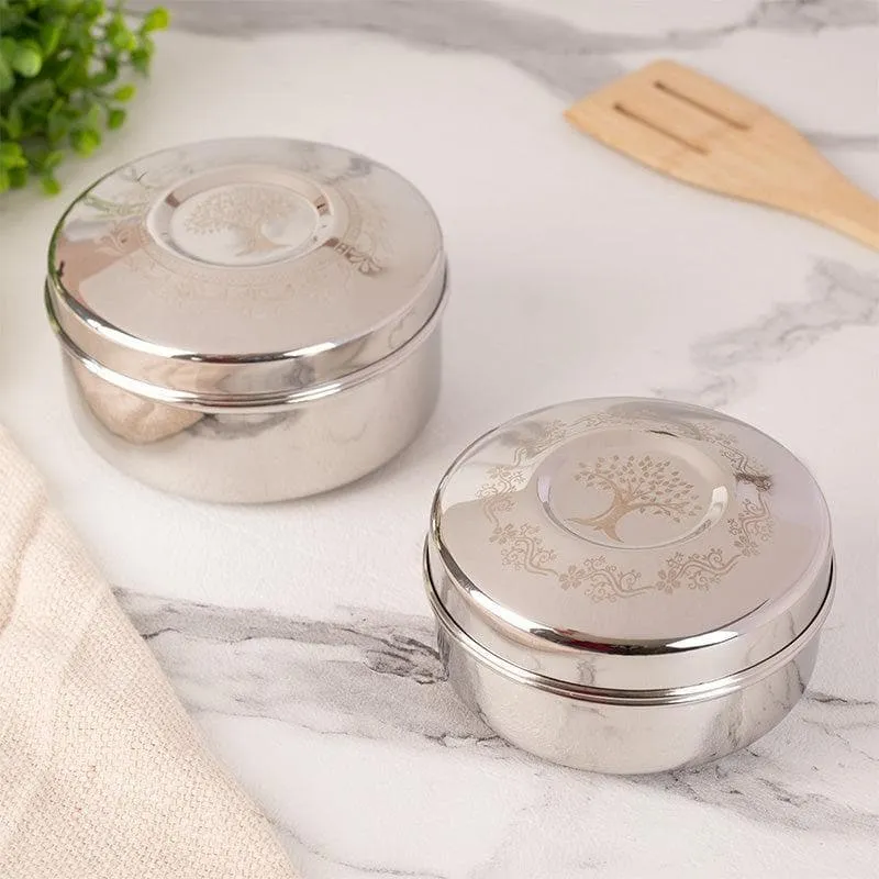 Two closed silver containers with decorative tree of life lids