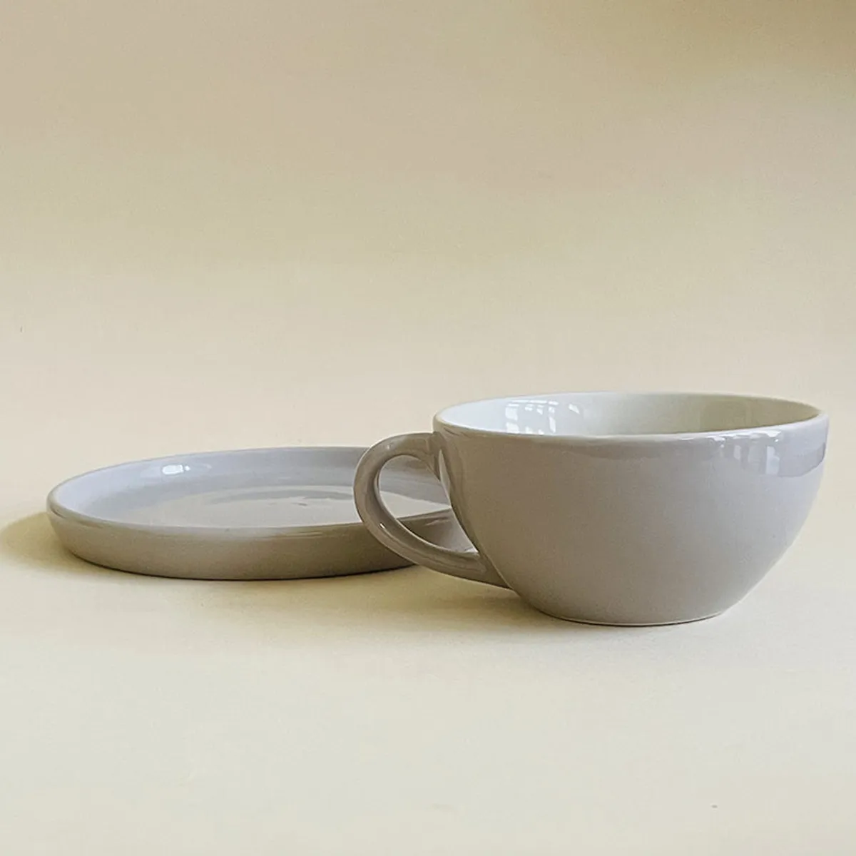 Grey cup placed beside a matching saucer in close-up