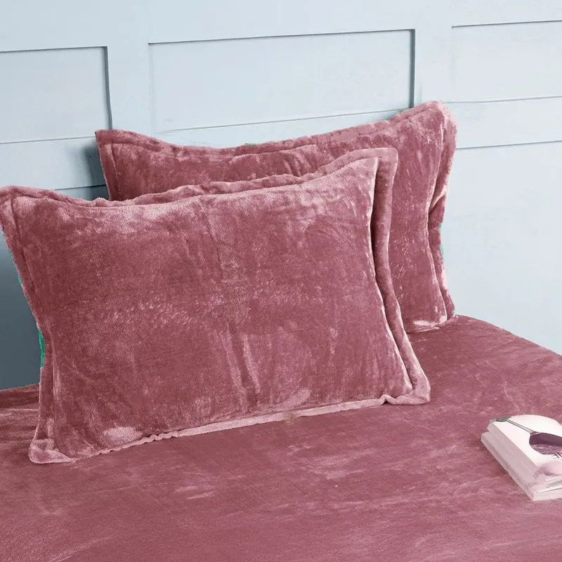 Two matching pink velvet pillow covers on the bedsheet