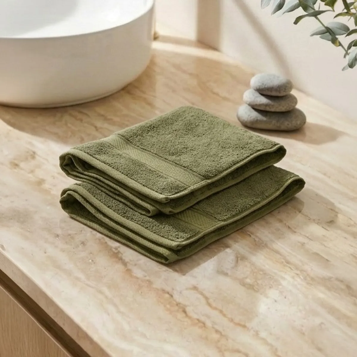Two folded olive green hand towels stacked on a bathroom counter