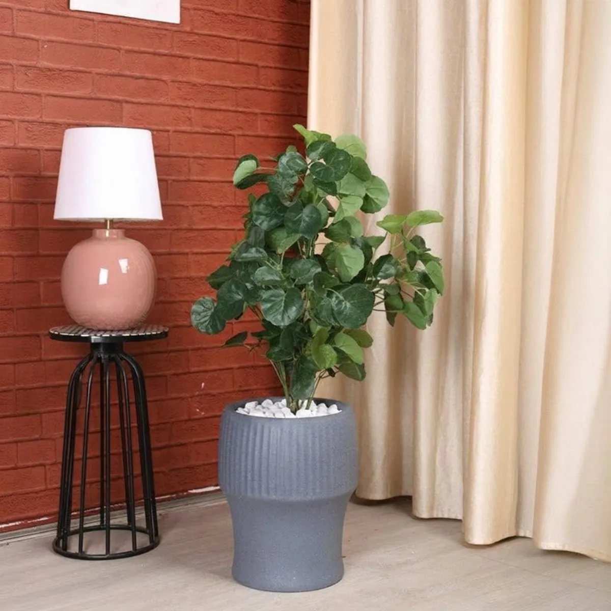 Grey ribbed planter with a leafy plant beside a lamp and curtains