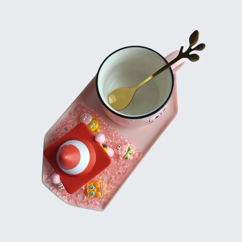 Top view of character mug, decorative figurine and spoon arranged on tray