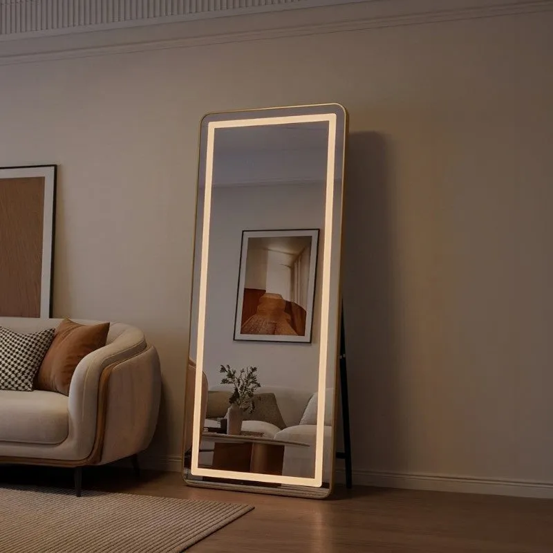 Illuminated floor mirror glowing beside a sofa in a dim room