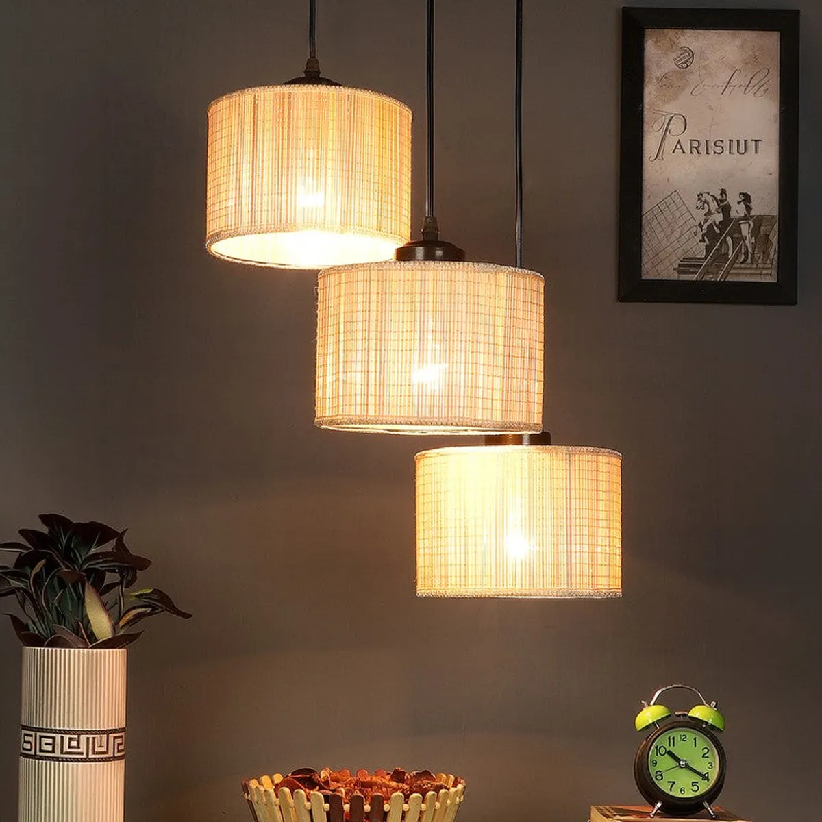 Three-light beige ceiling lamp glowing warmly in a styled room