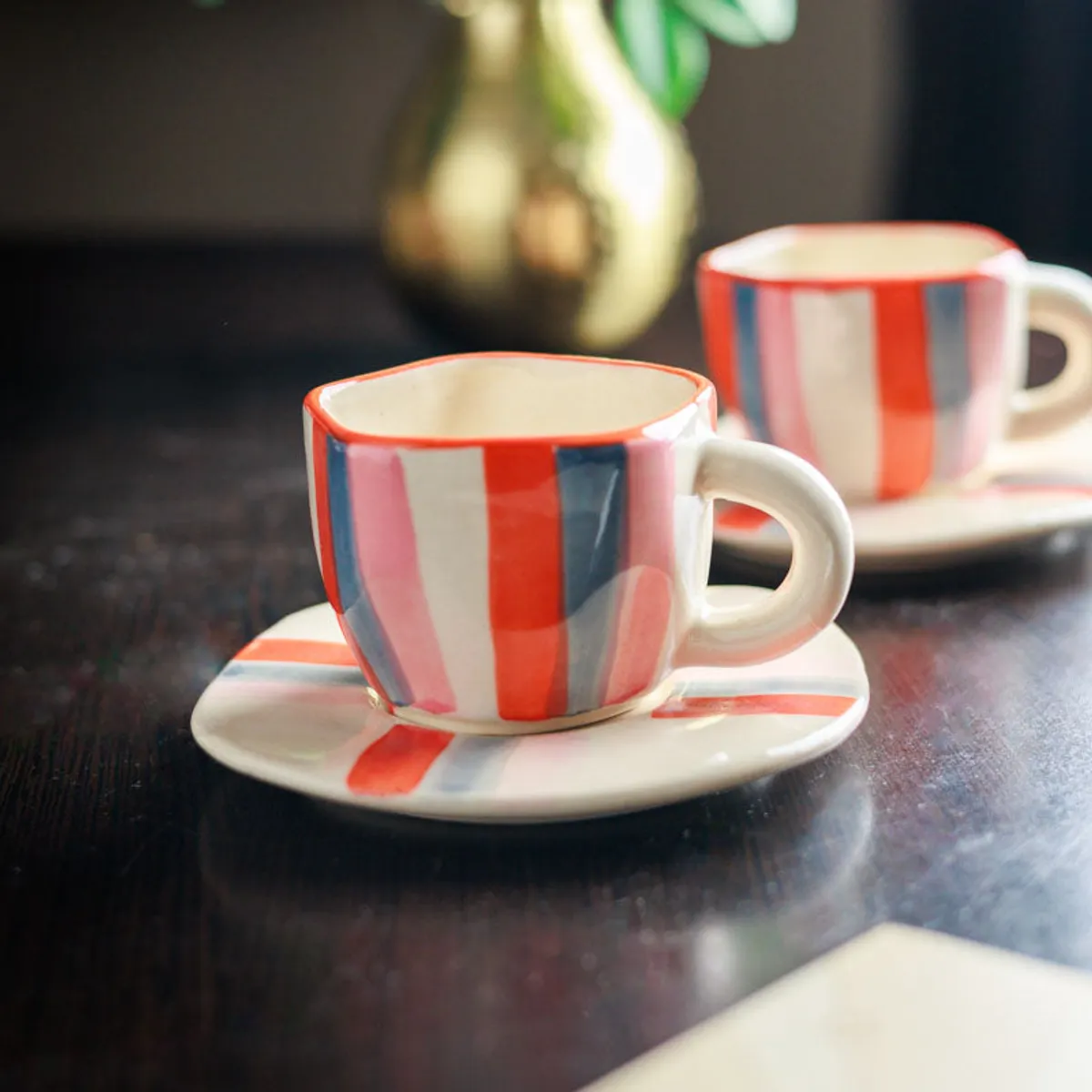 Striped ceramic cup and saucer in the foreground with a second set behind