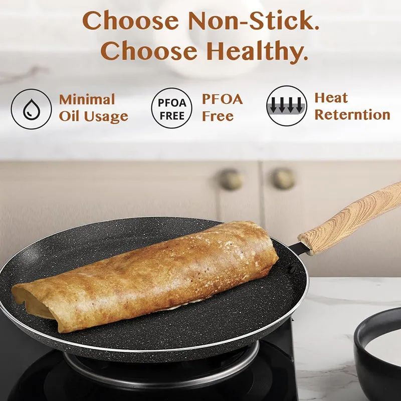 Dosa cooking on the black non-stick tawa placed on a stovetop