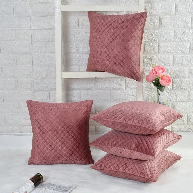 Five pink diamond-quilted cushion covers arranged on a white shelf and surface