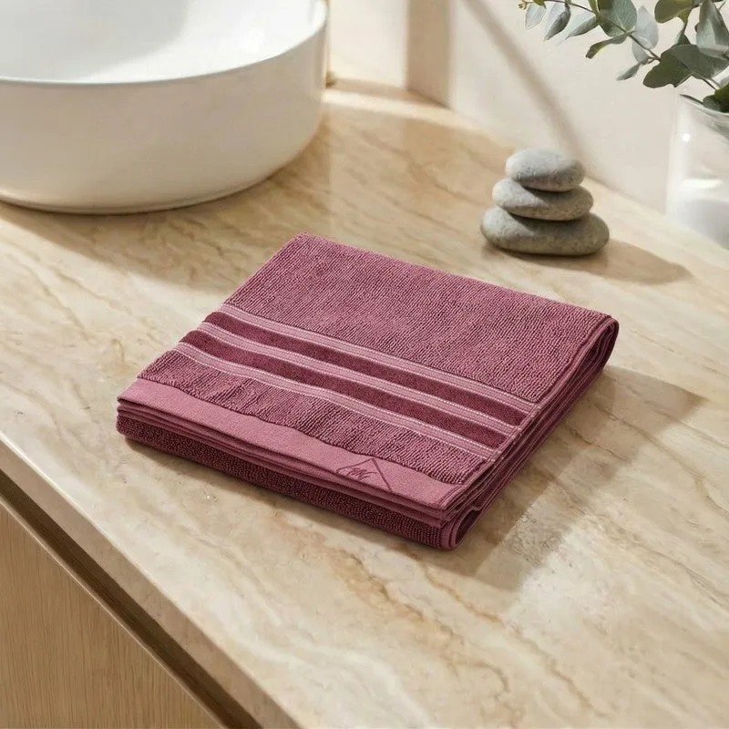 Folded maroon bath towel displayed on a light stone bathroom counter