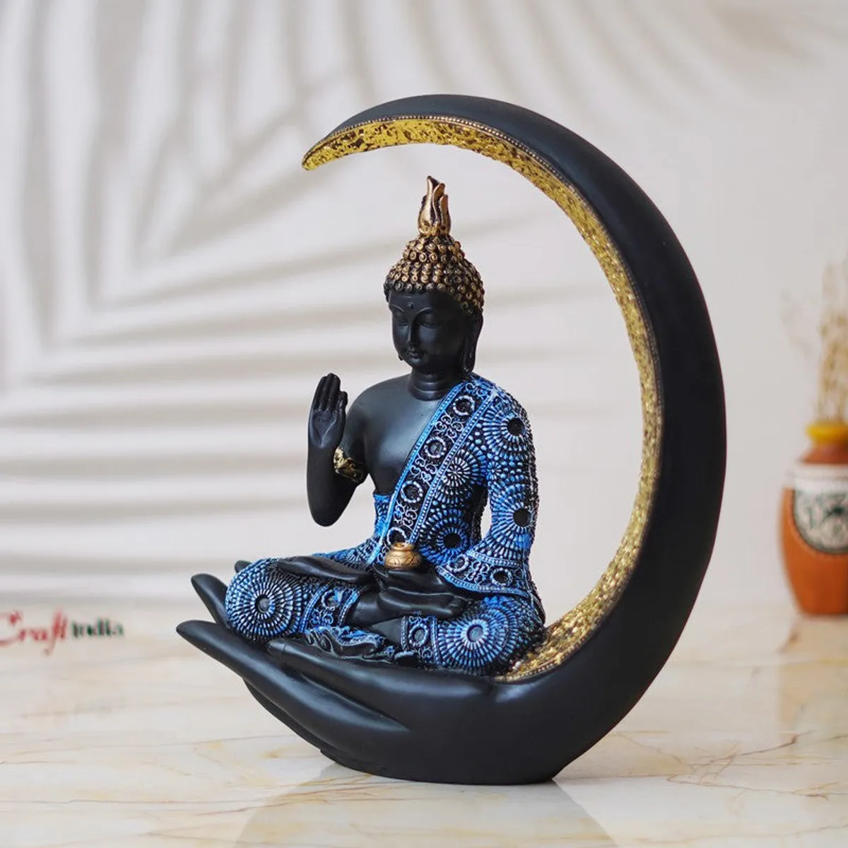 Angled view of black Buddha idol with blue detailing and gold crescent