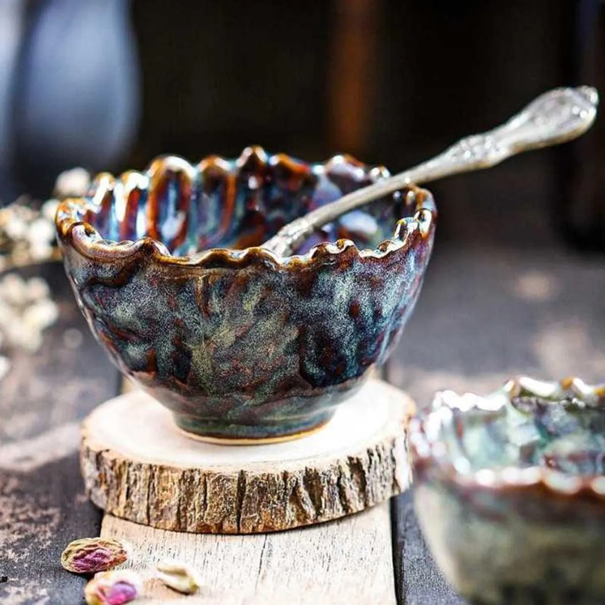 Glossy rippled ceramic snack bowl with a spoon, displayed on a wooden stand