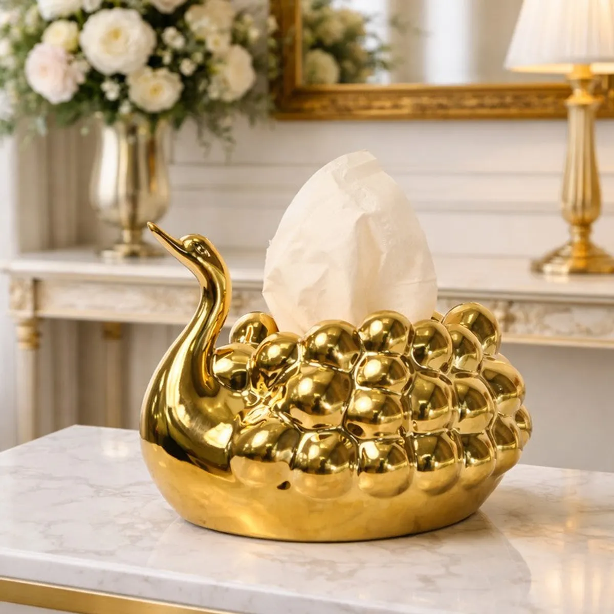 Gold swan tissue holder with a tissue displayed on a marble table
