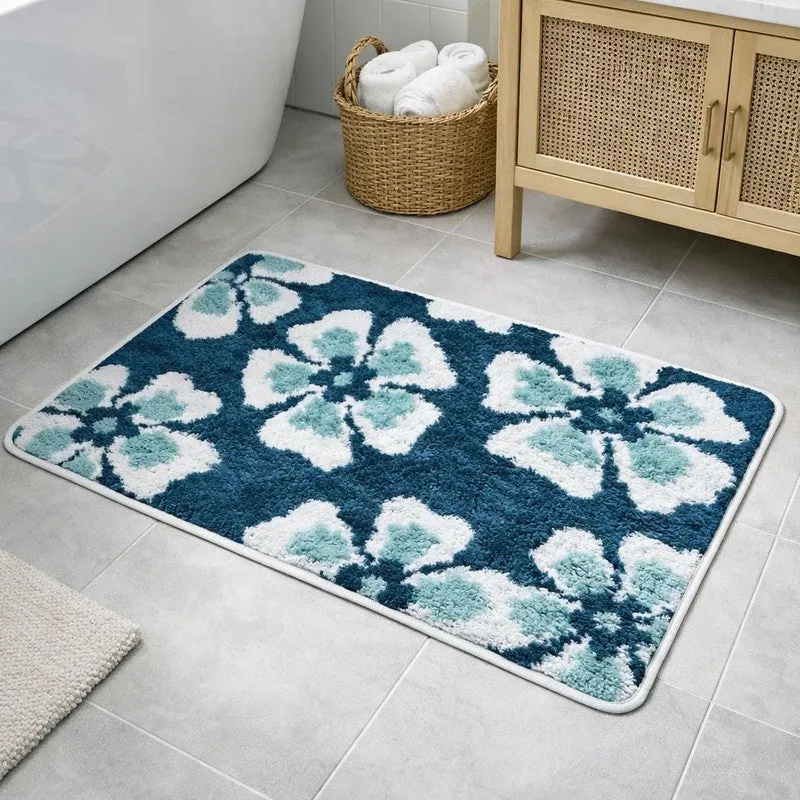 Rectangular green and white floral bath mat beside a bathtub
