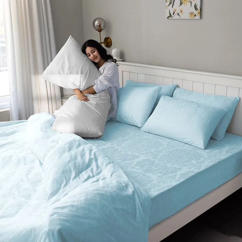 Woman sitting on a bed with pale blue floral bedsheet and matching pillow covers