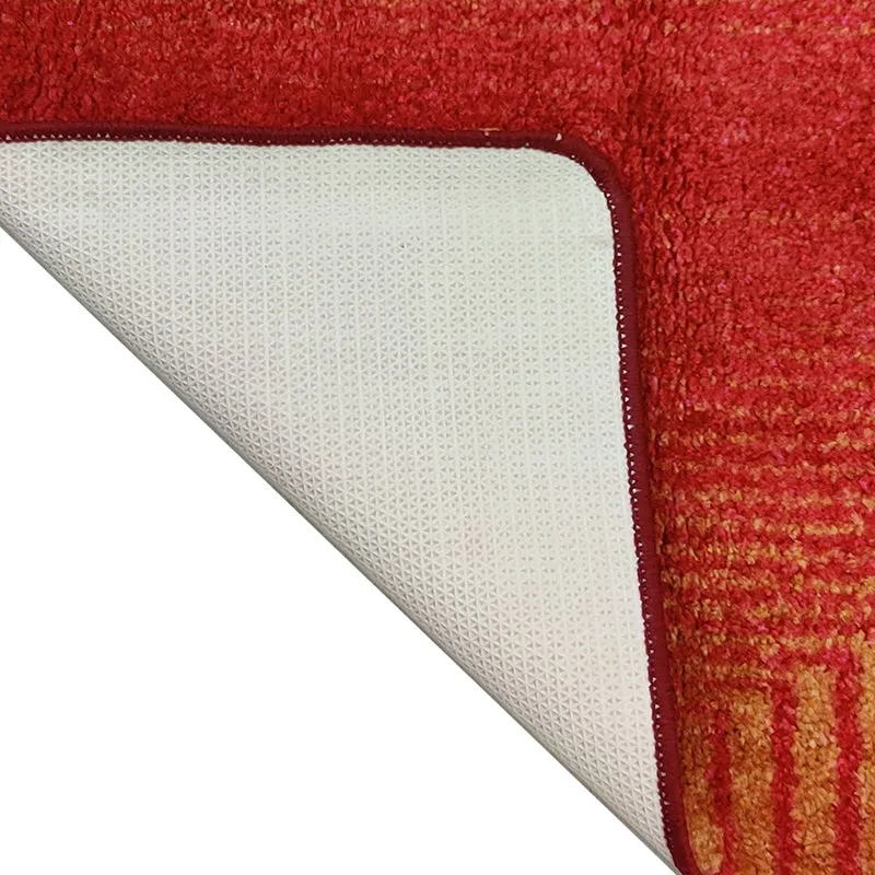 Close-up of the rug's pale textured backing and finished red edge