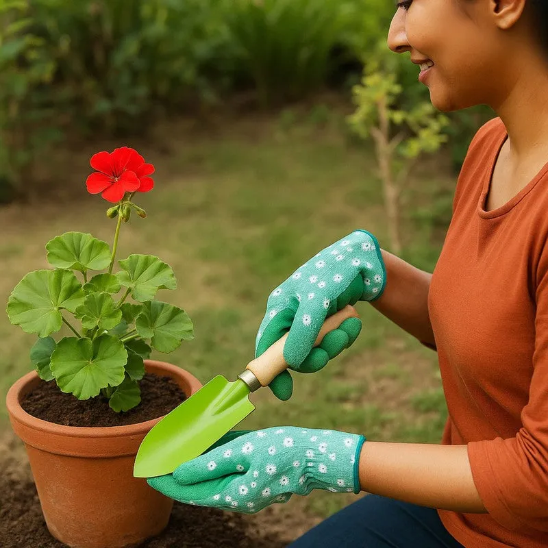 Gardener using the green trowel to plant a flowering plant in a terracotta pot.