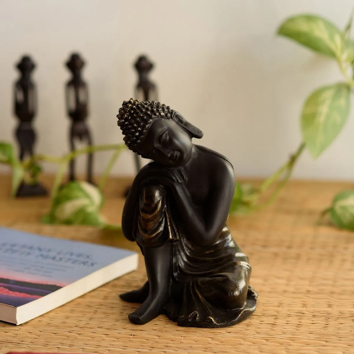 Black seated Buddha showpiece styled on a tabletop with plants