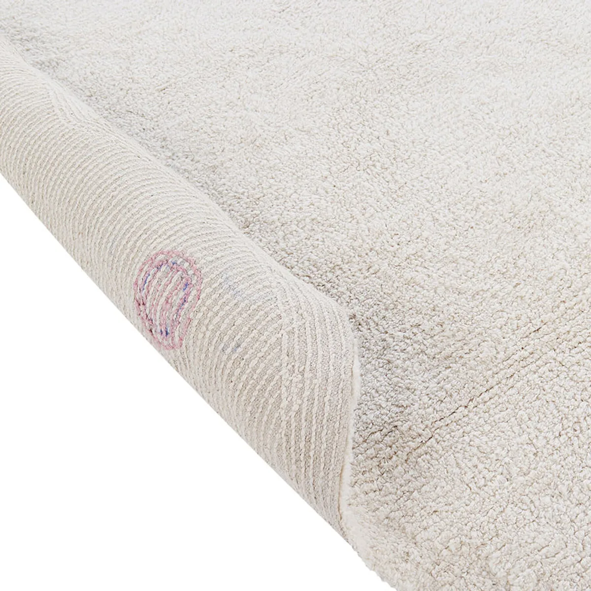Rolled edge of the white tufted rug showing its soft textured surface