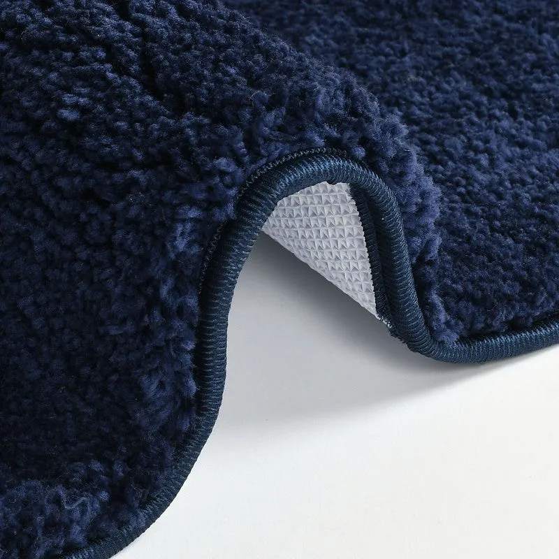 Corner view of the dark blue bath mat showing textured pile and backing