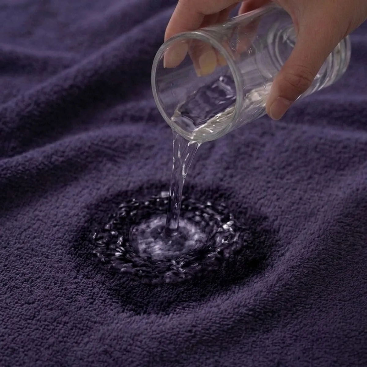 Water being poured onto the blue towel fabric to show absorbency
