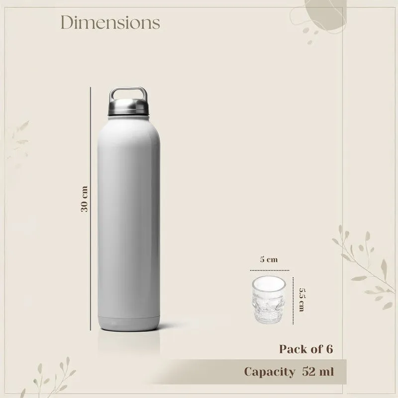 Clear skull-shaped shot glass shown beside a bottle for scale