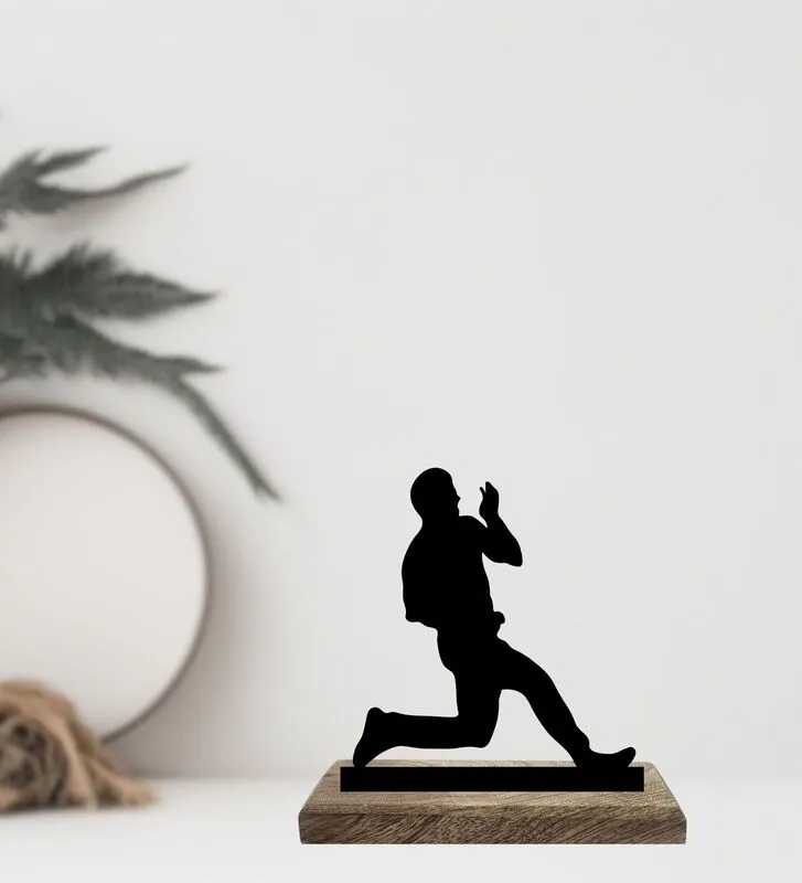 Black cricket bowler figurine on a wooden base against a soft neutral backdrop