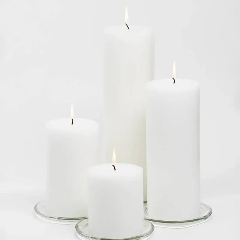 Four white pillar candles on clear glass plates against a white background