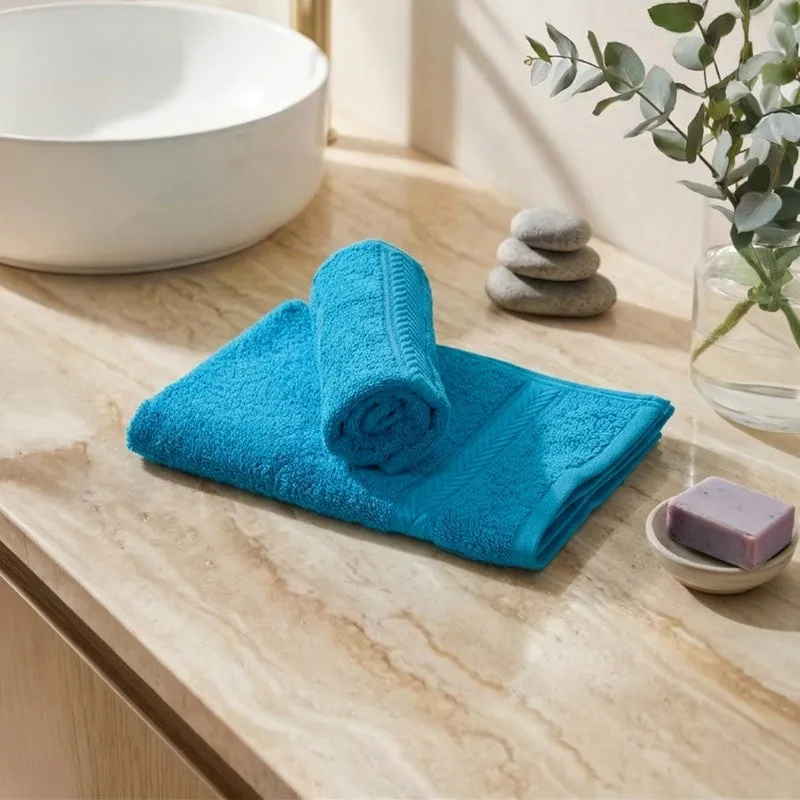 Blue hand towels folded on a bathroom counter beside a basin