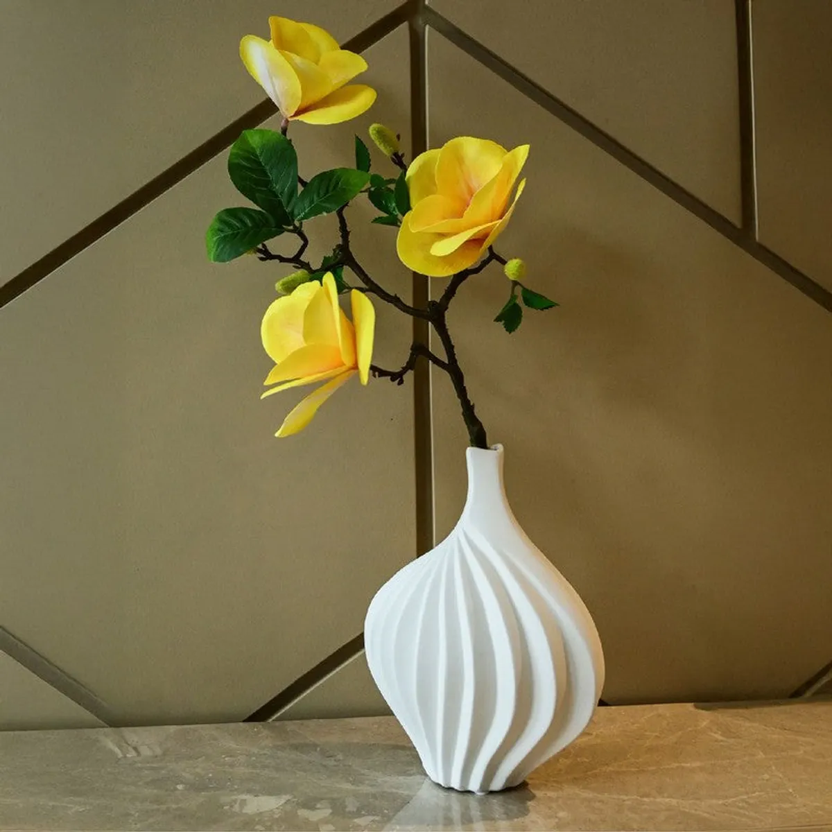 White ribbed vase with yellow flowers against a geometric wall