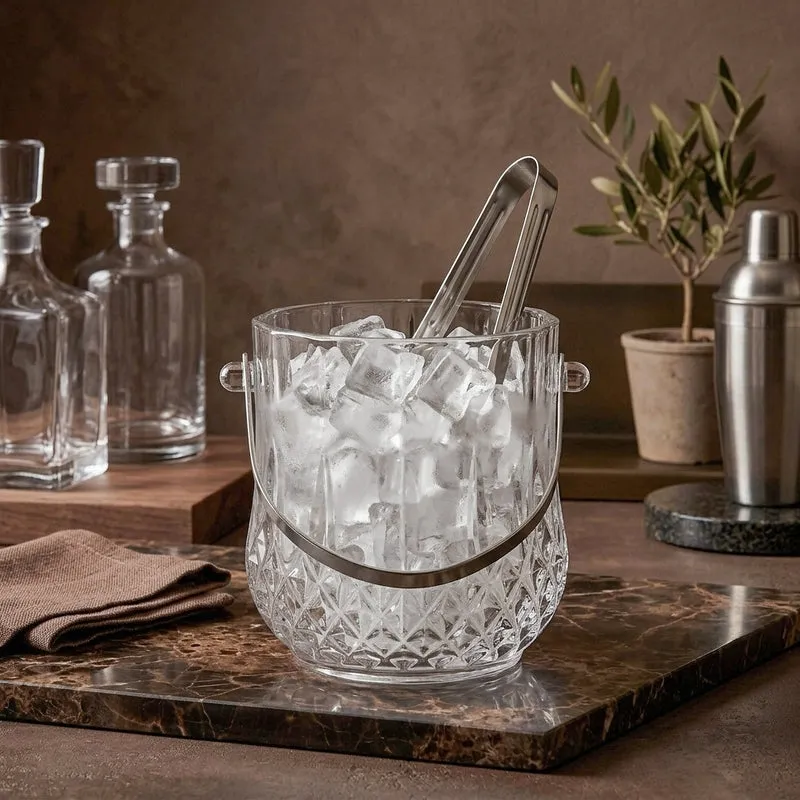 Glass ice bucket filled with ice and tongs on a bar counter