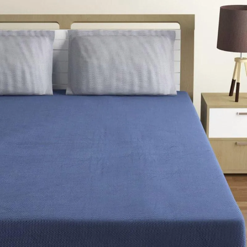 Navy blue bedsheet spread on a bed with two grey pillows
