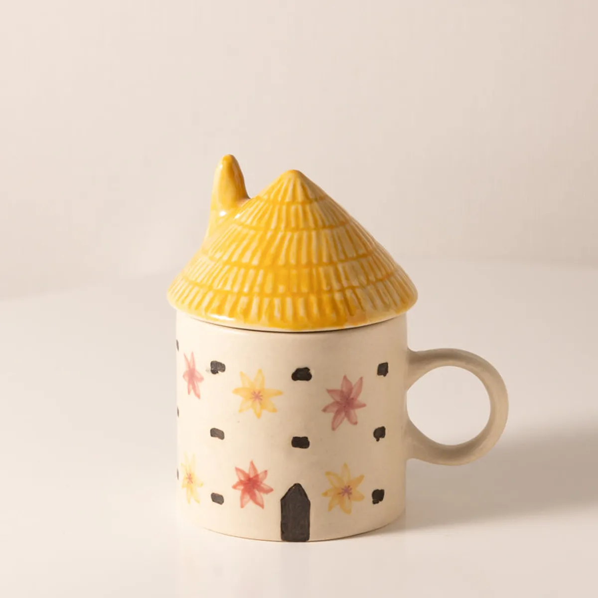 Front view of a cream ceramic cottage mug with yellow lid and handle
