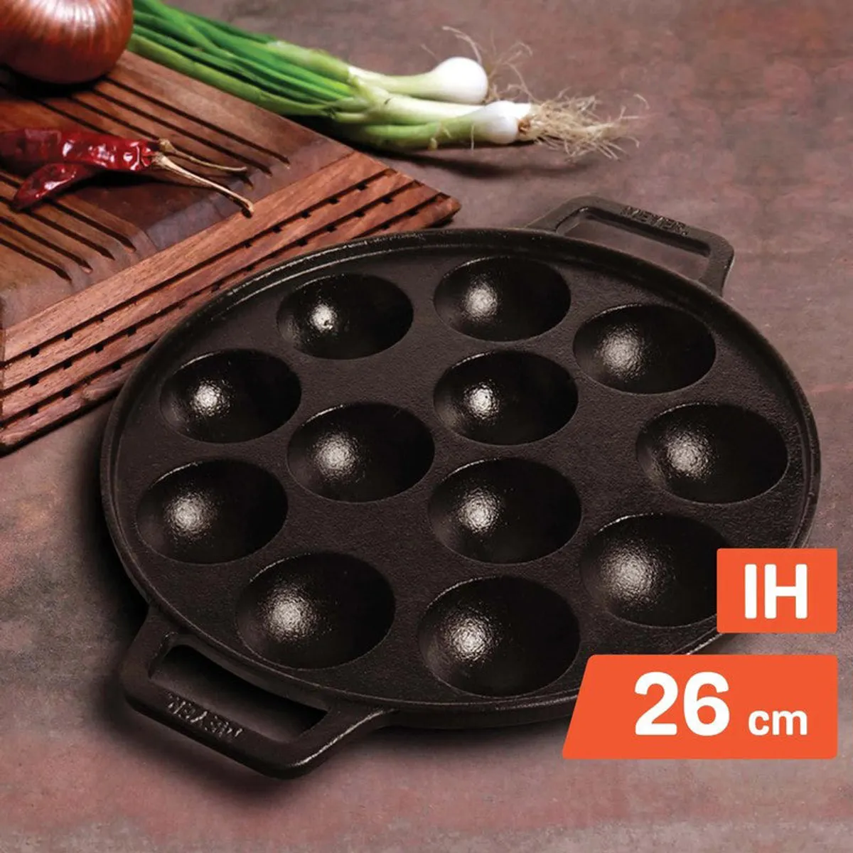 Black cast iron paniyaram pan surrounded by cooking ingredients