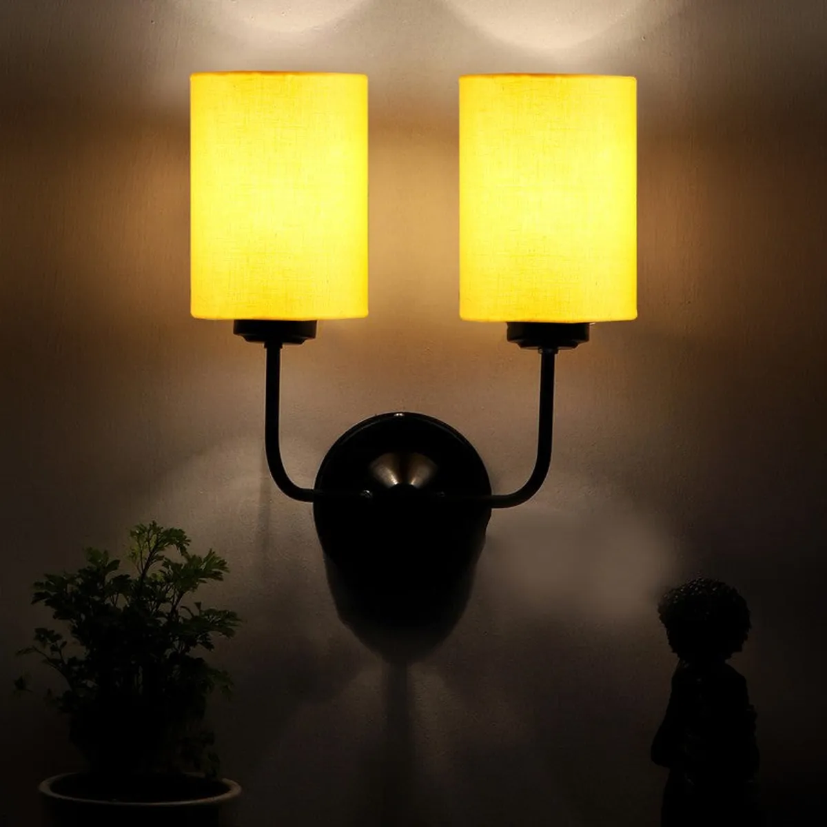 Glowing yellow twin-shade wall lamp in a dim setting