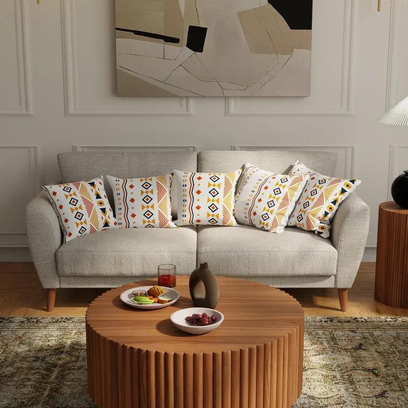 Five patterned cushion covers arranged on a light grey sofa in a neutral living room