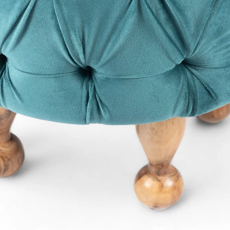 Close-up of turned wooden legs beneath blue ottoman