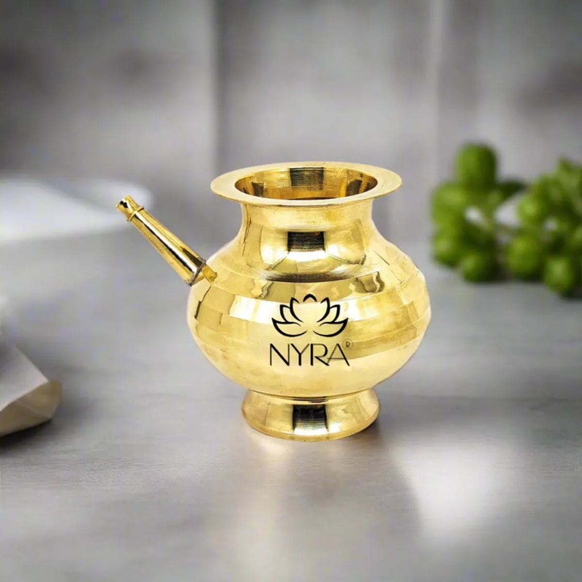 Polished brass kalasa shown close-up with an open rim and side spout