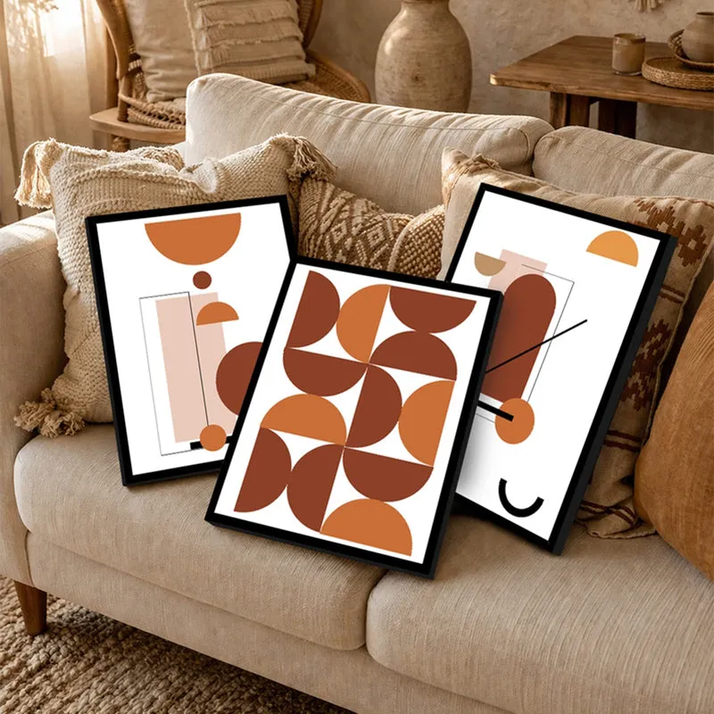 Three black-framed abstract prints leaning on a beige sofa