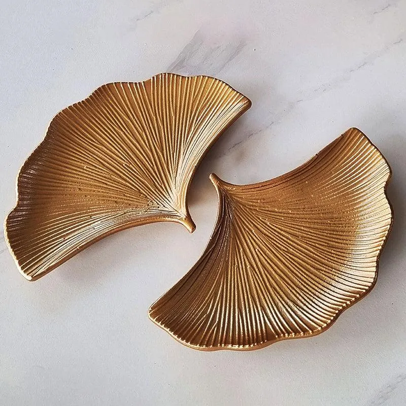 Two empty gold ginkgo leaf-shaped platters displayed side by side