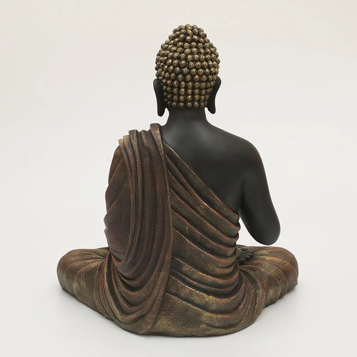 Rear view showing the Buddha idol's robe folds and textured hair.